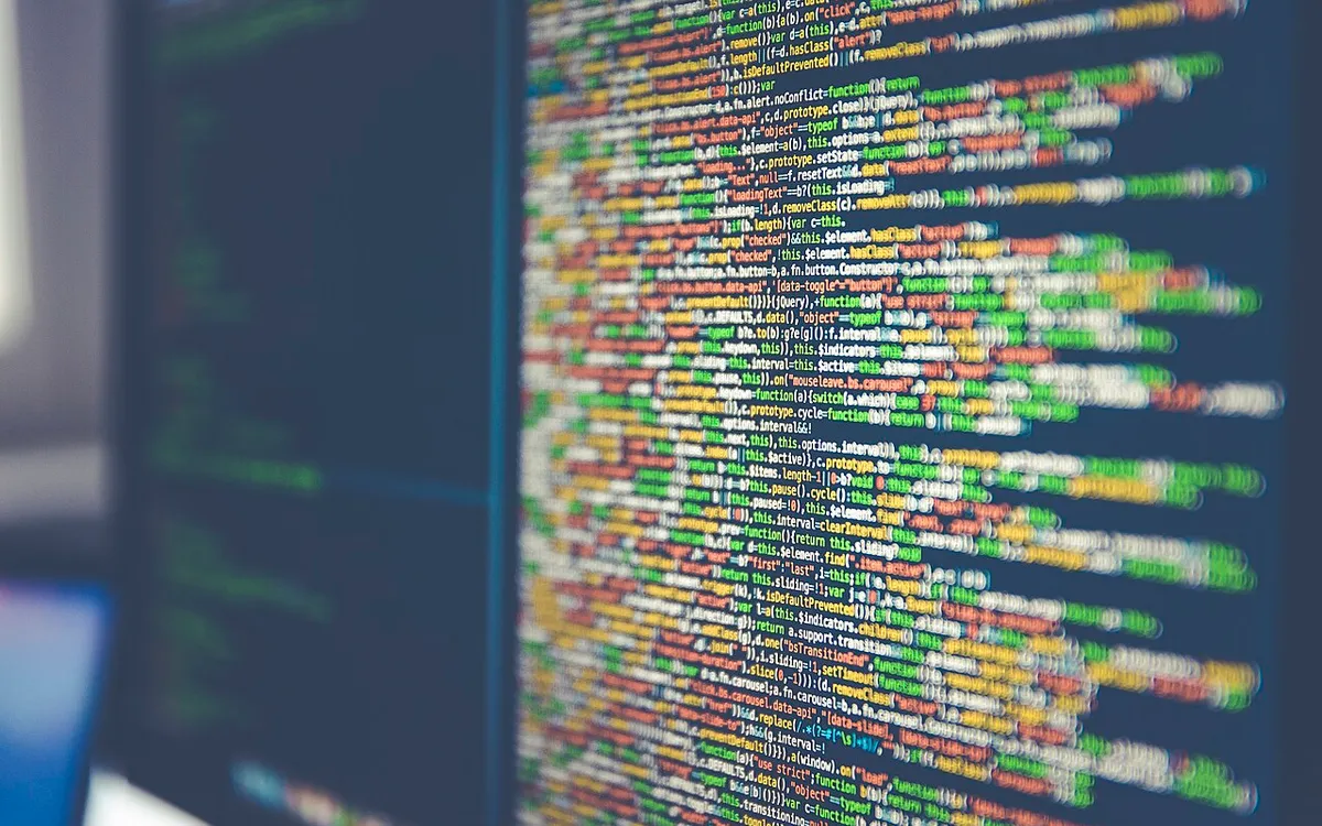 Lines of colour-highlighted source code on a computer monitor, shot at an angle with shallow focus